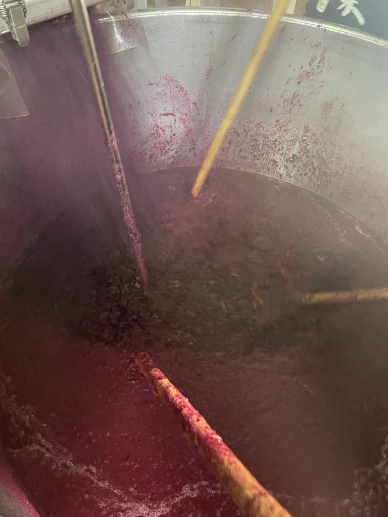 紫芋を2次がけ用タンクにて混ぜ合わせている様子。色が赤紫色をしており、使用した芋の粘度が強く、蒸した芋を混ぜあわせているため蒸気が立っている。